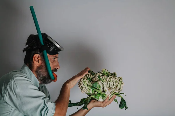 Человек в маске держит цветную капусту — стоковое фото