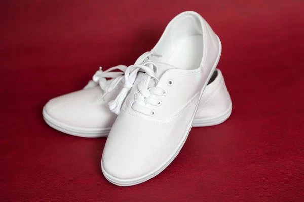 Coppia di sneakers bianche in piedi su sfondo rosso . — Foto Stock