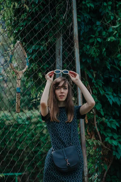 Young slim girl stands in front of tennis court — Stock Photo, Image