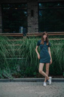 Yeşil elbiseli ince uzun kız cadde boyunca yürüyor