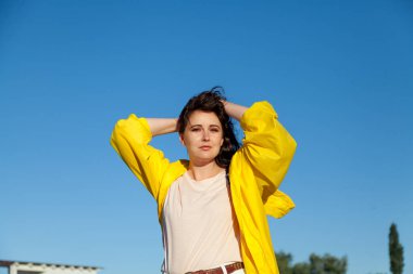 Mavi gökyüzüne karşı sarı ceket güzel artı boyutu kadın