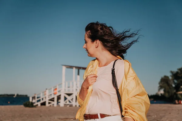 Hermosa mujer de tamaño grande en chaqueta amarilla en la playa de arena — Foto de Stock