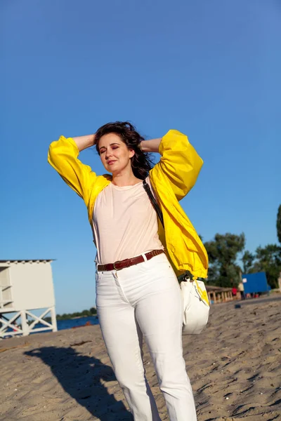 Mooie plus size vrouw in gele jas op zandstrand — Stockfoto