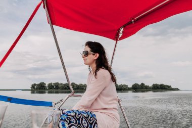 Pembe bluzlu güzel kahverengi saçlı kadın gölgelik altında oturur