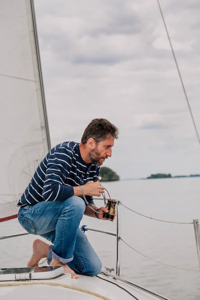 Чоловік сидить на луці вітрильної яхти і виглядає надворі — стокове фото