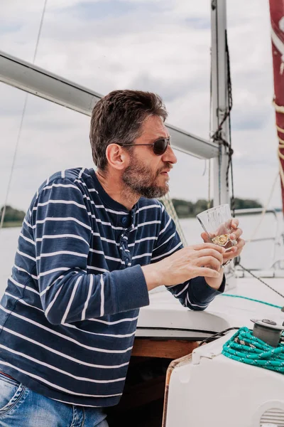 Чоловік з бородою в окулярах п'є віскі на яхті — стокове фото