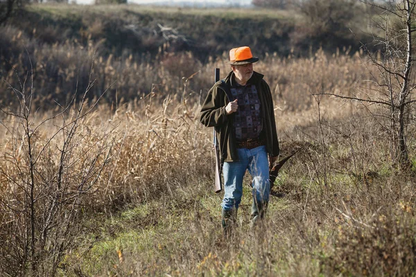 Elderly hunter with wild bird in orange hat — Stock Photo, Image