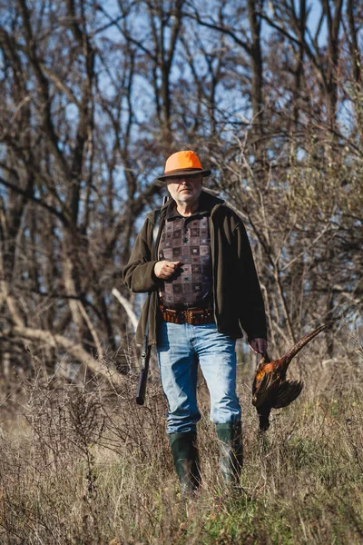 Älterer Jäger mit Wildvogel mit orangefarbenem Hut — Stockfoto