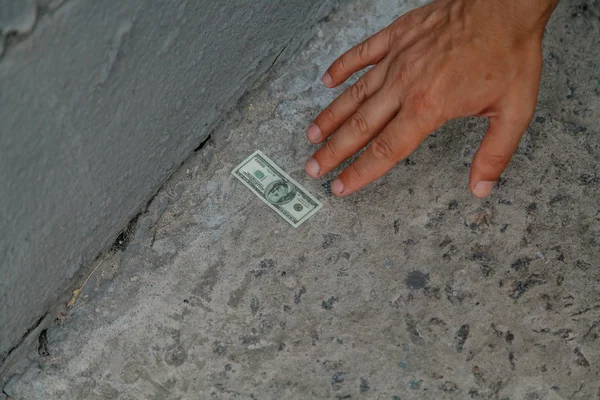 Hand reaches for bill on concrete — Stock Photo, Image