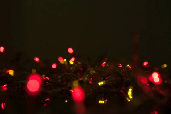 Brilho guirlanda colorido elétrico na superfície preta — Fotografia de Stock