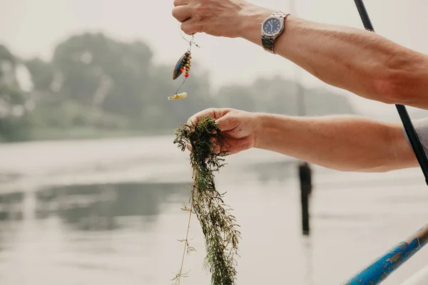 Pescador elimina algas de la caña de pescar en barco —  Fotos de Stock