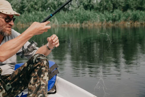 Fisherman unravels knots on fishing line — Stock Photo, Image