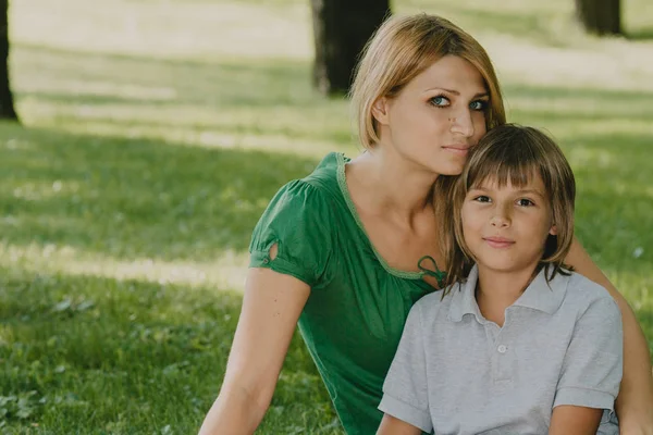 Familjeporträtt. Mamma och son på grön gräsmatta — Stockfoto