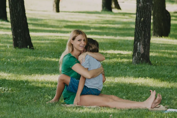 長い白い髪を持つ若い母親は草の上に息子を抱きしめる — ストック写真