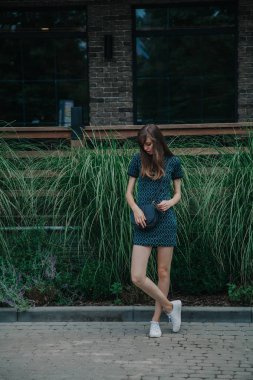 Yeşil elbiseli ince uzun kız cadde boyunca yürüyor