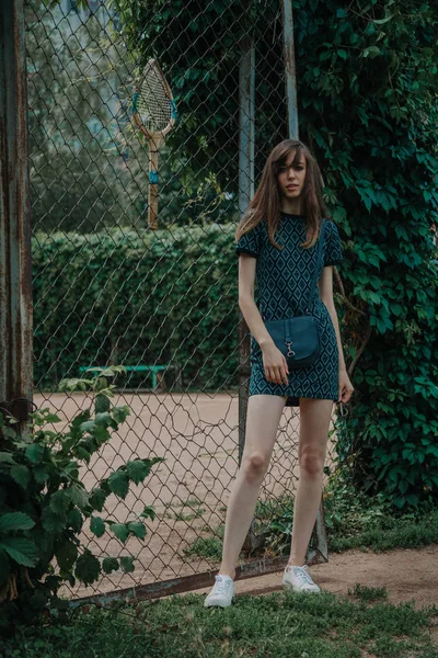 Young slim girl stands in front of  tennis court — Stock Photo, Image