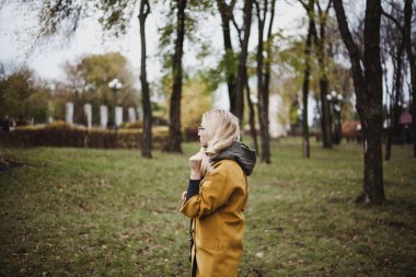 Sevimli sarışın sonbahar parkta yürüyor