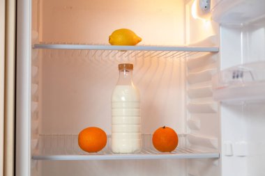 Boş buzdolabında süt şişesi ve meyve seti