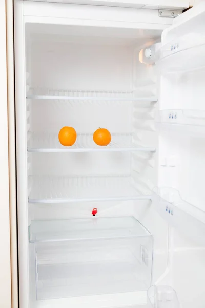 Two oranges lie on empty shelf of  refrigerator — Stock Photo, Image