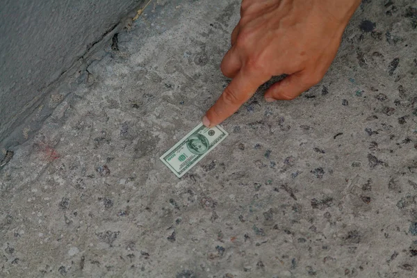 Hand reaches for bill on concrete — Stock Photo, Image