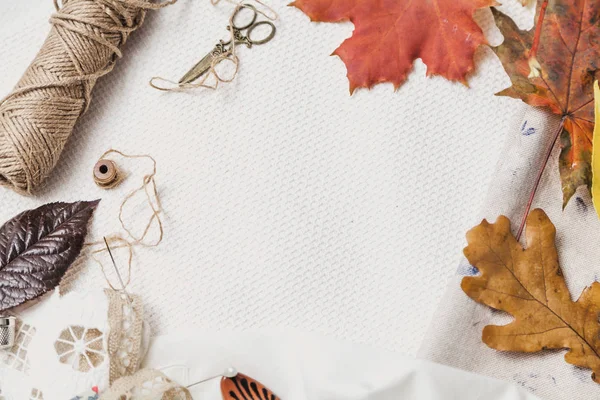 はさみ、糸、落ち葉が白い布の上に横たわっている — ストック写真