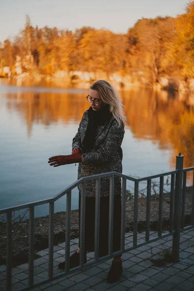 Slim rubia está de pie en la orilla del estanque de otoño — Foto de Stock