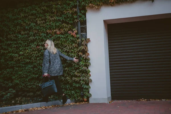 Snygga blonda promenader framför Green Hedge — Stockfoto