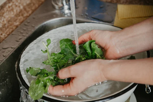 Manos de mujer lavando hojas verdes de rúcula — Foto de Stock