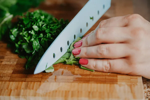 Woman hands are cutting  green leaves of arugula — Stock Photo, Image