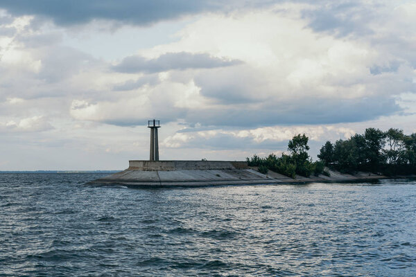 Lighthouse on edge of concrete breakwater on wide river