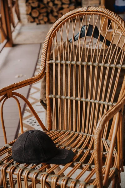 Boné com viseira encontra-se na cadeira de vime na varanda — Fotografia de Stock