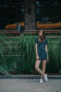 Yeşil elbiseli ince uzun kız cadde boyunca yürüyor