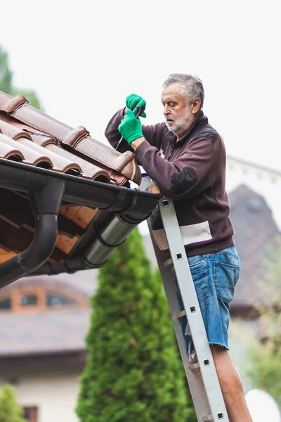L'homme répare un toit carrelé de la maison close up — Photo