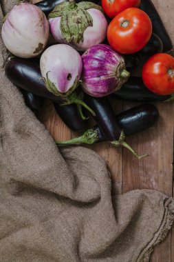 Mavi ve beyaz patlıcan tahtalarda yatıyor. Çantanın yanında