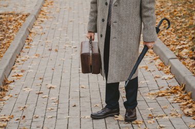 Meydan sokakta halı çanta ve şemsiye ile adam duruyor