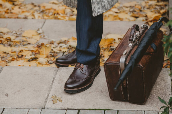 Legs of man and carpetbag in autumn park