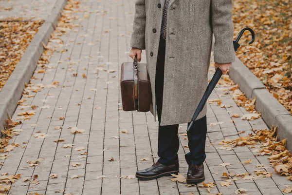 Meydan sokakta halı çanta ve şemsiye ile adam duruyor