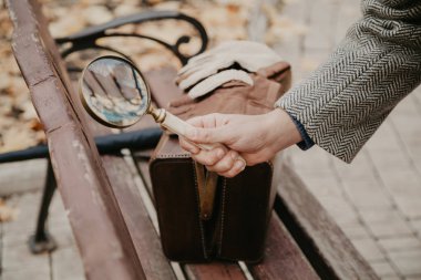 Dedektif el ahşap park bankı üzerinde büyüteç tutar