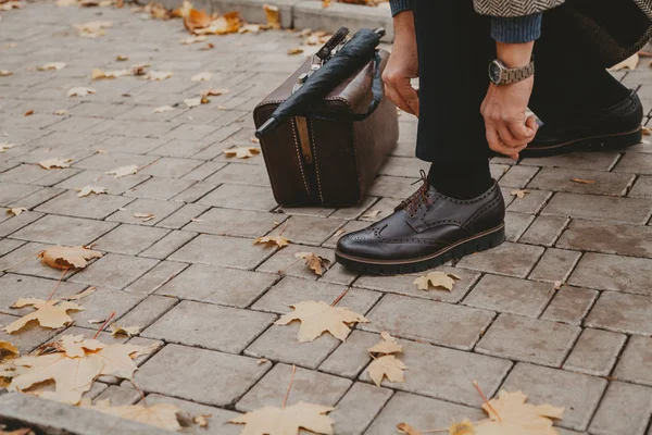 Beyefendi kahverengi ayakkabıya dantel bağlıyor. Yakında halı çantası var. — Stok fotoğraf