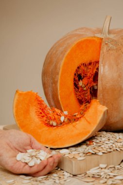 Olgun dilimlenmiş kabak gemide yatıyor. Yakındaki el tohumları tutun