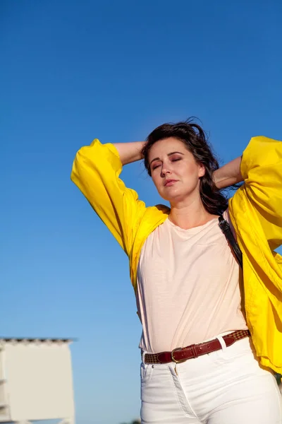 Vacker plus size kvinna i gul jacka mot blå himmel — Stockfoto