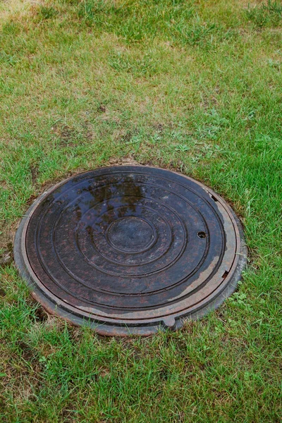 Closed sewer well on grass — Stock Photo, Image