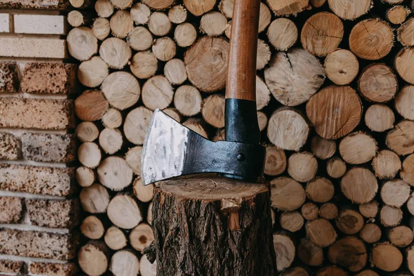 Een bijl staat op een stomp temidden van gestapeld brandhout — Stockfoto
