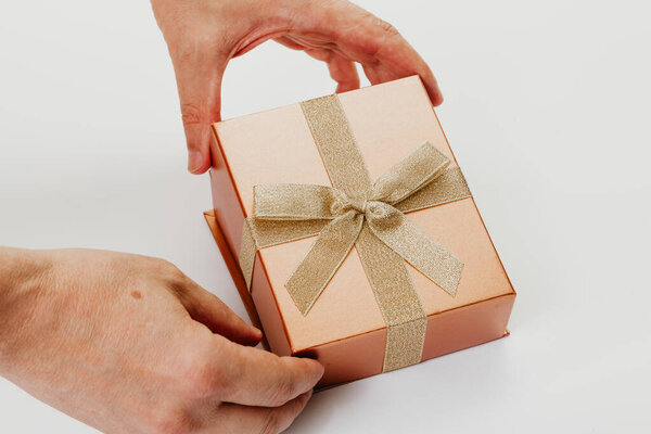 Hands open box with ribbon bow on white background