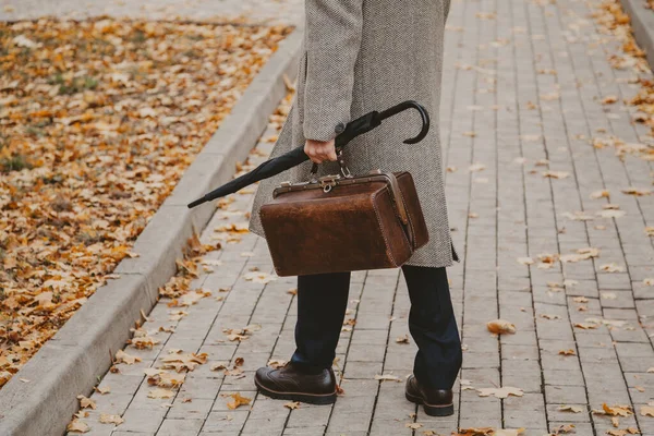Homem com saco de carpete e casaco está de pé no beco de outono — Fotografia de Stock
