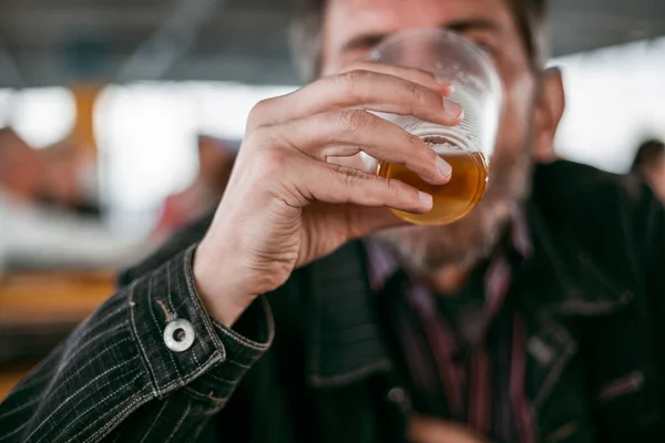 Человек пьет пиво из пластиковой чашки — стоковое фото