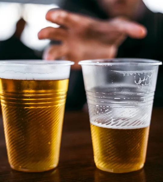 Two plastic glasses with beer stand side by side