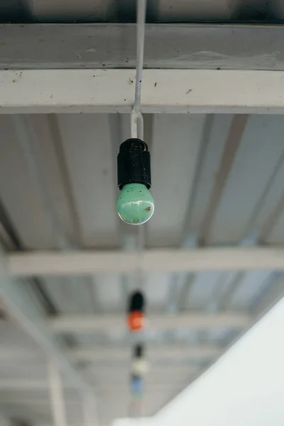 Green electric lamp weighs under the profile roof