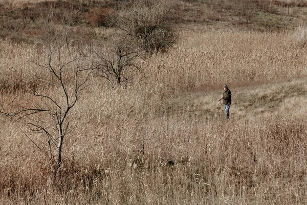 Metsästäjä ase rinteessä umpeen kuiva pitkä ruoho — kuvapankkivalokuva