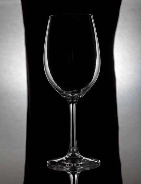 Skleněné víno sklo stojí na skle na černém pozadí — Stock fotografie